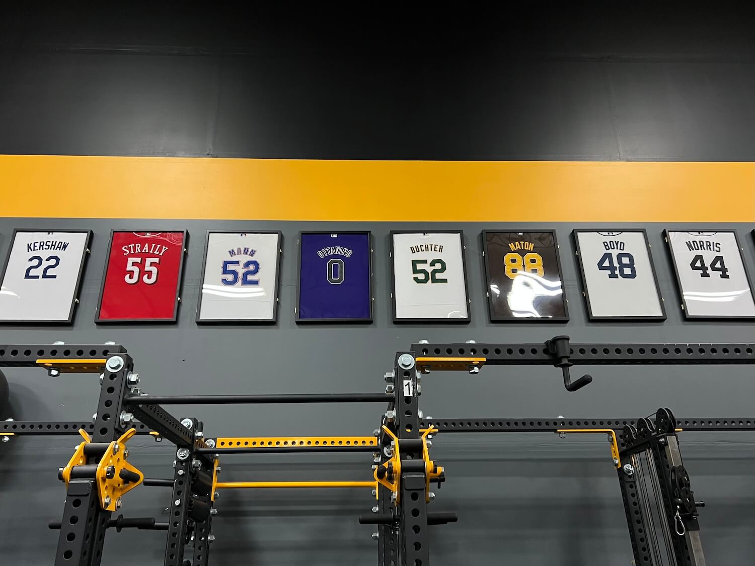 Framed jerseys of notable alums line the cinder block walls.
